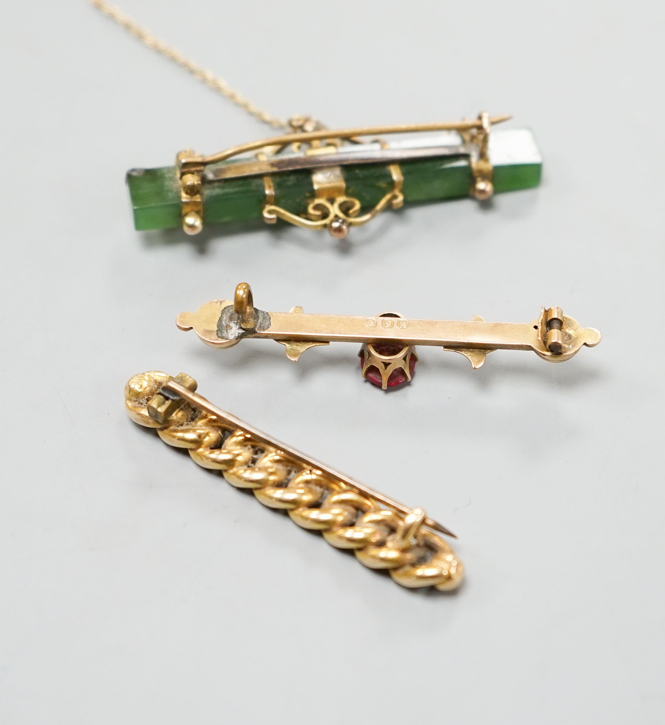 An Edwardian 15ct interwoven bar brooch, 45mm gross 4.2 grams, a mounted nephrite bar brooch and one other bar brooch.